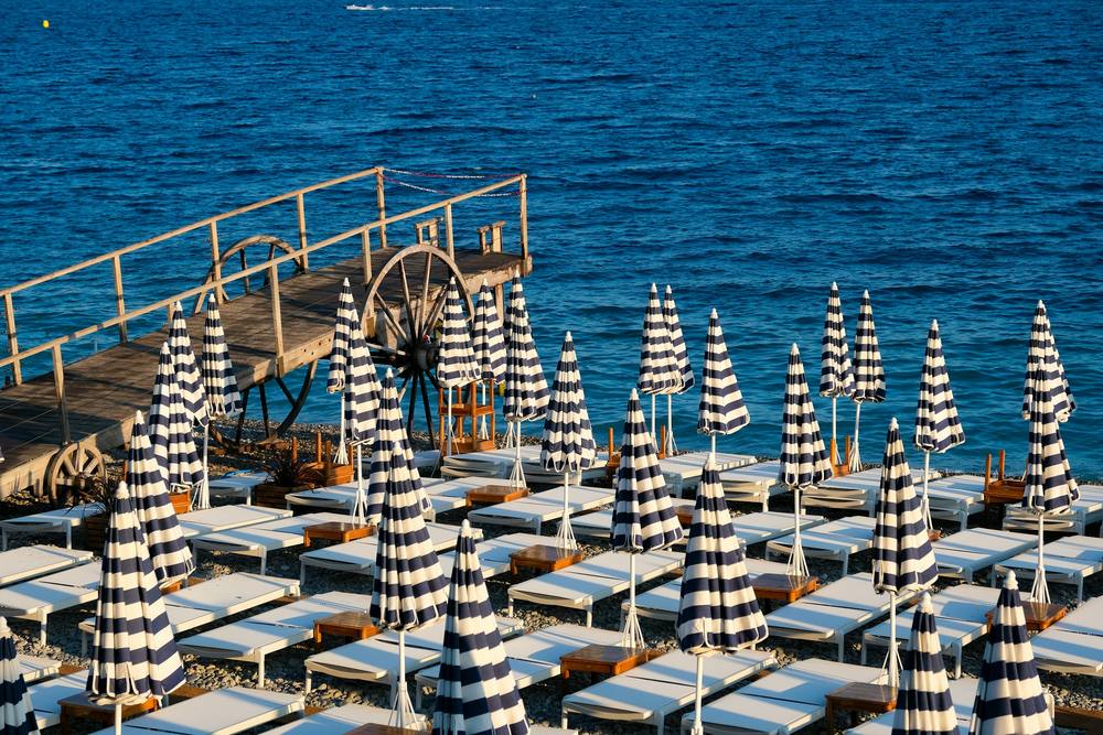 Beach club mediterráneo con sombrillas de rayas junto al mar