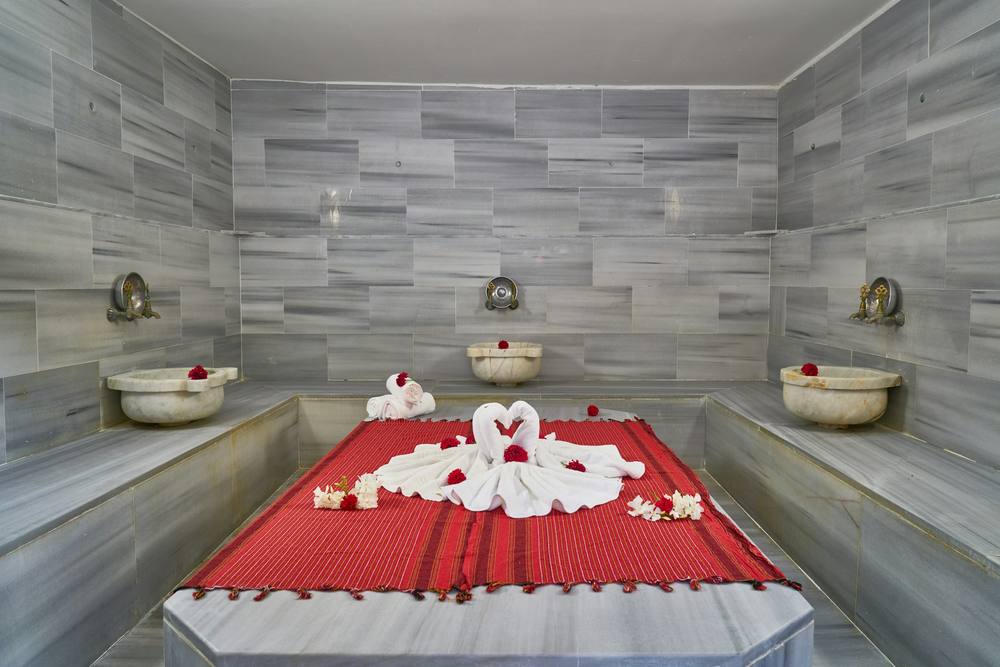 Hammam turco de mármol con un peştemal rojo sobre la piedra central